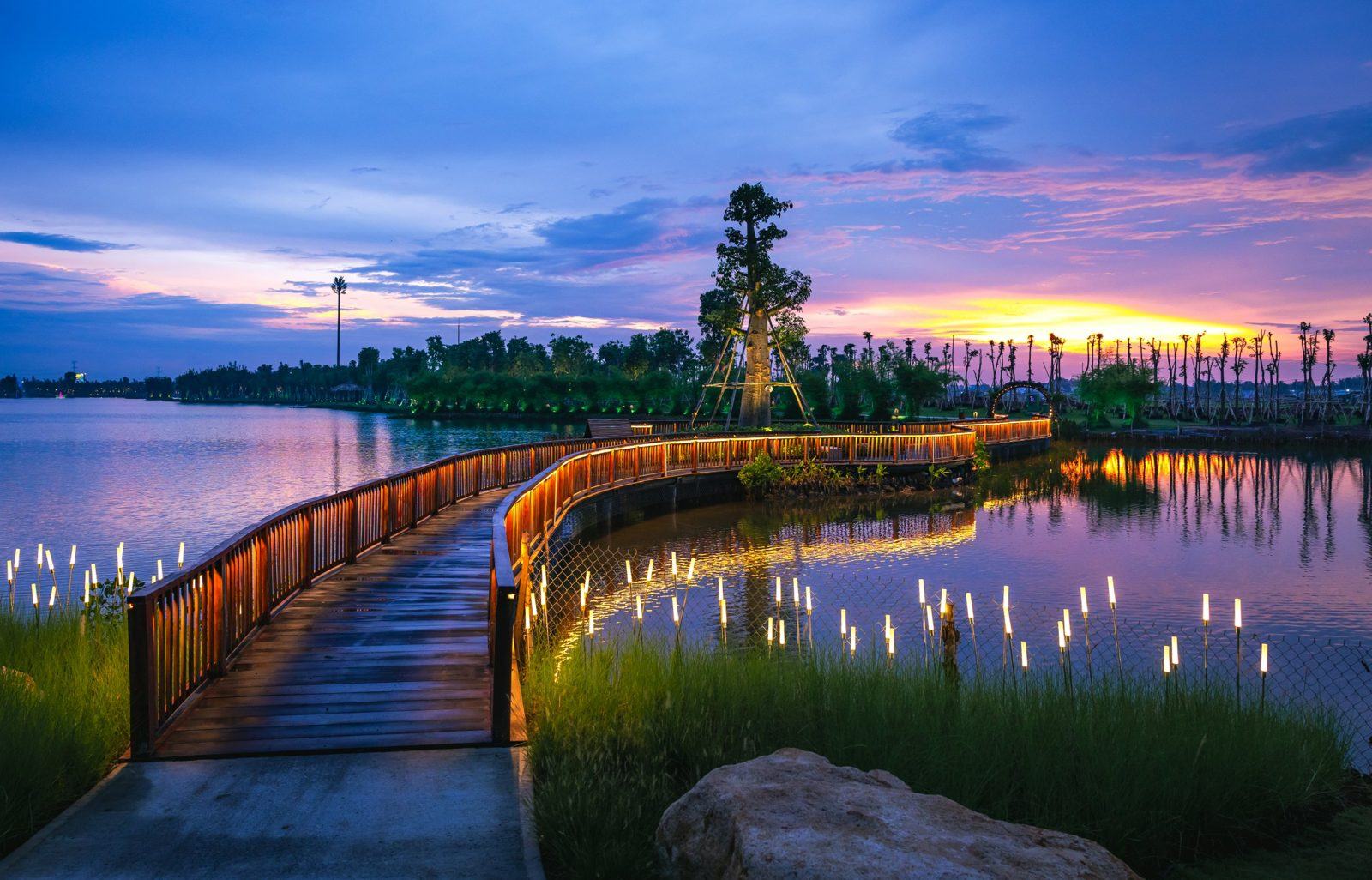 Cầu gỗ phát sáng ven hồ lúc hoàng hôn tại Eco Retreat